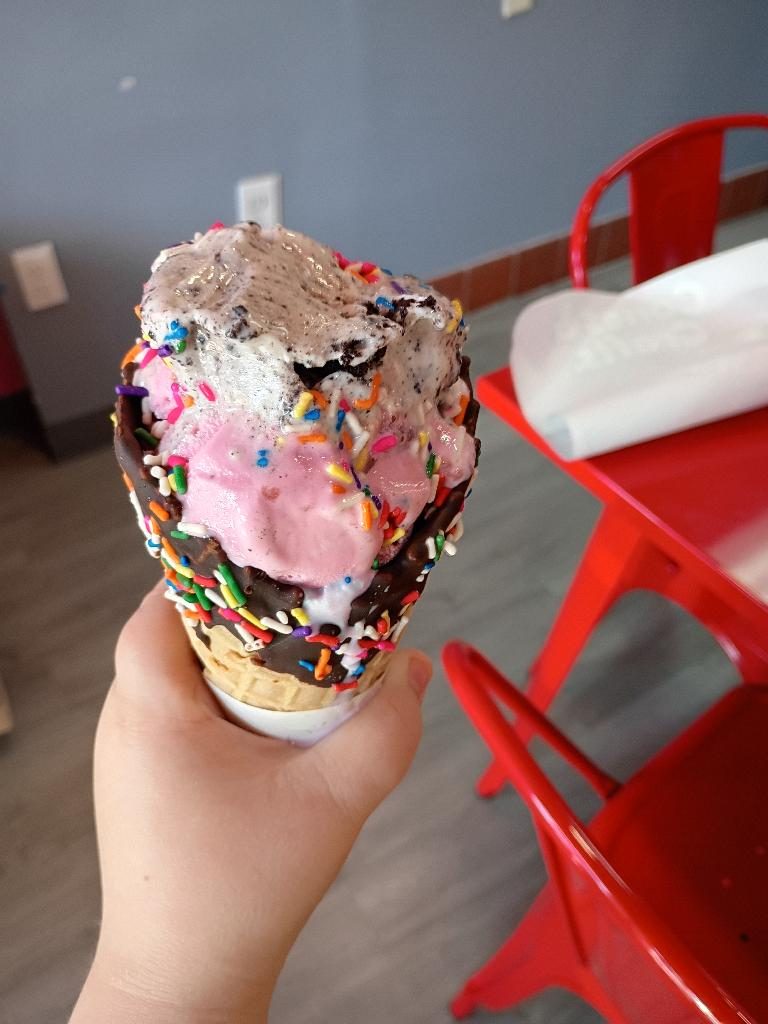 A loaded ice cream cone topped with sprinkles at Scoops
