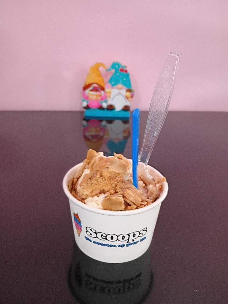 A Scoops sundae cup piled high with ice cream and toppings